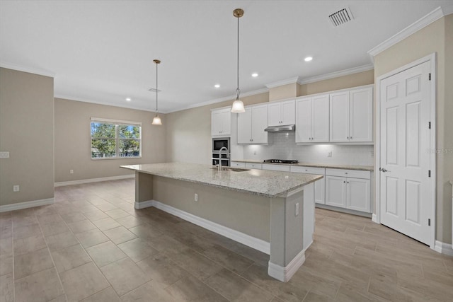 kitchen with decorative light fixtures, light stone countertops, an island with sink, and white cabinets