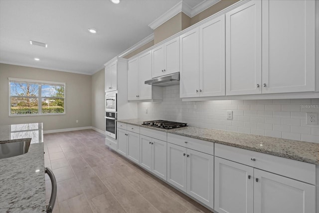 kitchen with white cabinetry, stainless steel appliances, crown molding, and light stone countertops