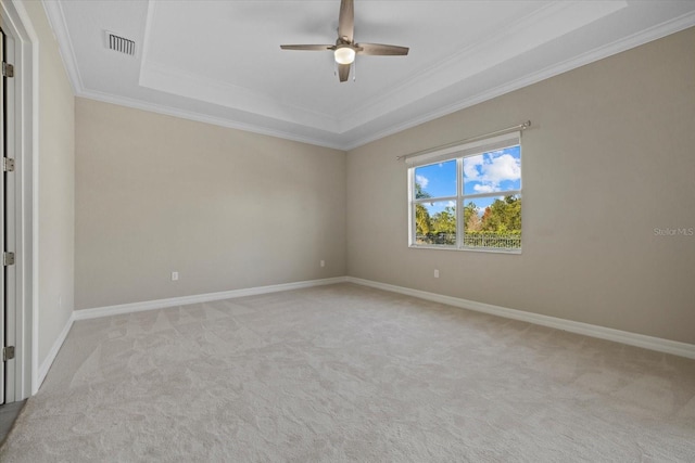 carpeted spare room with crown molding, ceiling fan, and a tray ceiling