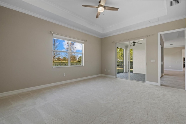 carpeted spare room with a raised ceiling, ornamental molding, and ceiling fan