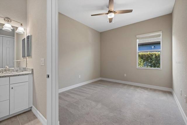 unfurnished room featuring ceiling fan, light colored carpet, and sink