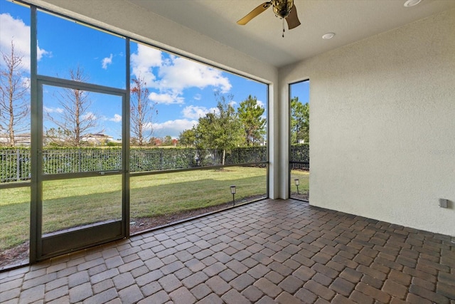 unfurnished sunroom featuring ceiling fan and plenty of natural light