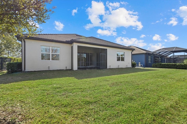 back of property featuring glass enclosure and a lawn