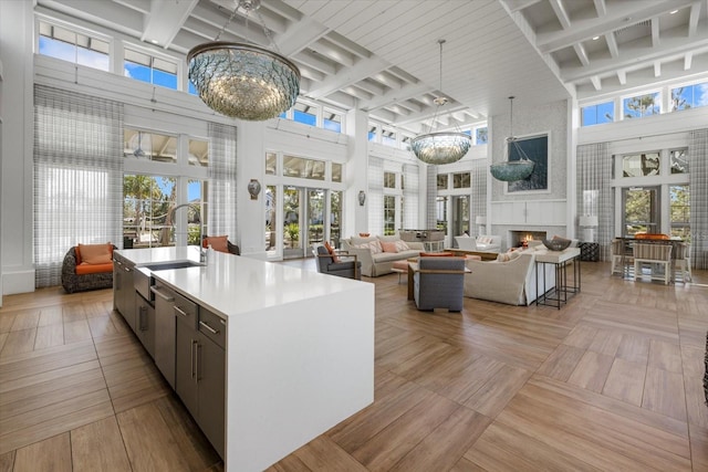 kitchen with sink, a high ceiling, a fireplace, a center island with sink, and french doors