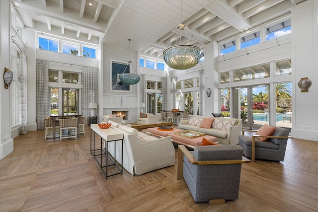 interior space featuring a notable chandelier, beam ceiling, a fireplace, and french doors