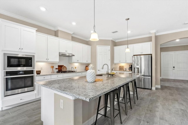 12029 Perennial Pl, Lakewood Ranch, FL 34211 - kitchen featuring appliances with stainless steel finishes, a sink, under cabinet range hood, a spacious island, and arched walkways