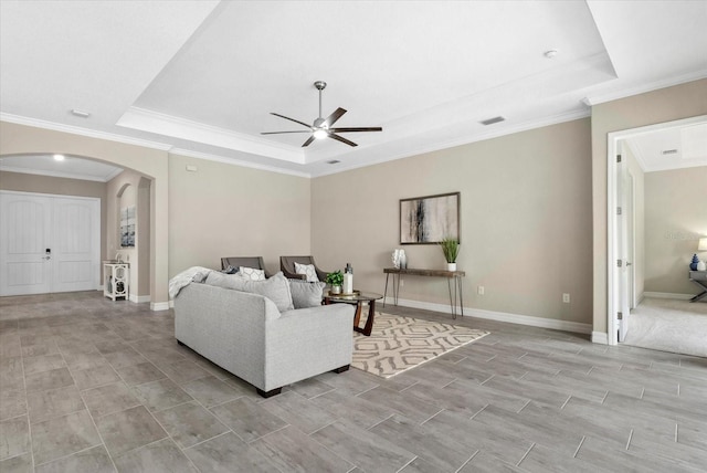 12029 Perennial Pl, Lakewood Ranch, FL 34211 - living area with a tray ceiling, arched walkways, ceiling fan, crown molding, and baseboards