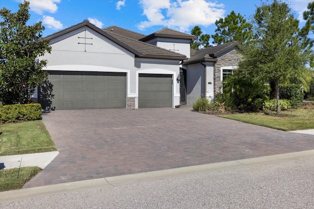 12029 Perennial Pl, Lakewood Ranch, FL 34211 - view of front of property with stone siding, stucco siding, a garage, decorative driveway, and a tiled roof