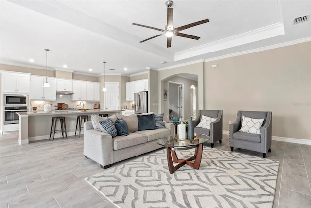 12029 Perennial Pl, Lakewood Ranch, FL 34211 - living room with arched walkways, a ceiling fan, a tray ceiling, crown molding, and recessed lighting
