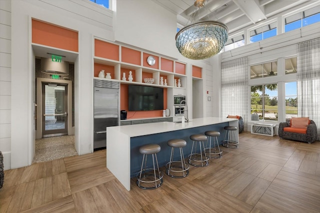 12029 Perennial Pl, Lakewood Ranch, FL 34211 - kitchen featuring stainless steel built in refrigerator, a towering ceiling, light countertops, a chandelier, and an island with sink