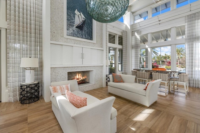 12029 Perennial Pl, Lakewood Ranch, FL 34211 - living area featuring a towering ceiling, a lit fireplace, and wood finished floors
