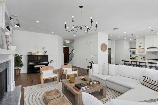 living area with a high end fireplace, wainscoting, visible vents, and stairs