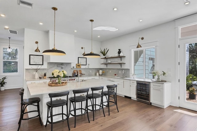 kitchen with open shelves, wine cooler, visible vents, and white cabinets