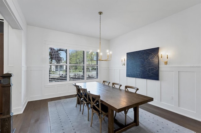 dining room featuring a wainscoted wall, a chandelier, a decorative wall, and dark wood-type flooring