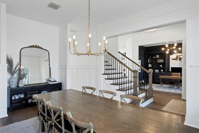 dining space with dark wood finished floors, visible vents, a notable chandelier, and a decorative wall