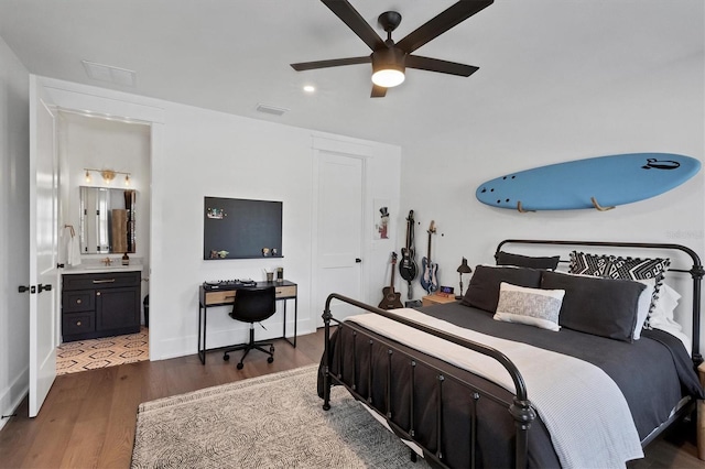 bedroom featuring dark wood-style floors, visible vents, ensuite bathroom, ceiling fan, and a sink