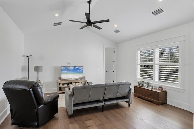 living room featuring lofted ceiling, visible vents, and wood finished floors