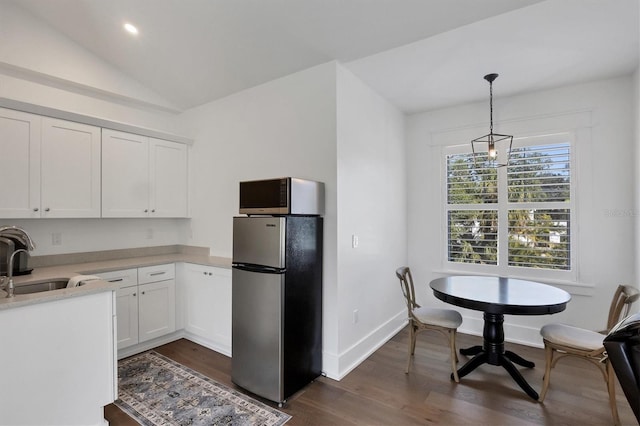 kitchen with white cabinets, lofted ceiling, hanging light fixtures, stainless steel appliances, and light countertops