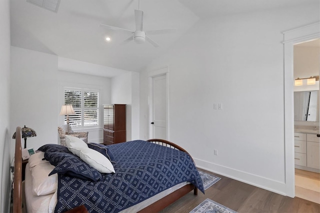 bedroom with lofted ceiling, connected bathroom, wood finished floors, visible vents, and baseboards