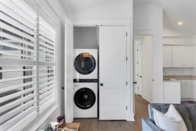 laundry room featuring recessed lighting, laundry area, a sink, stacked washer / drying machine, and dark wood finished floors