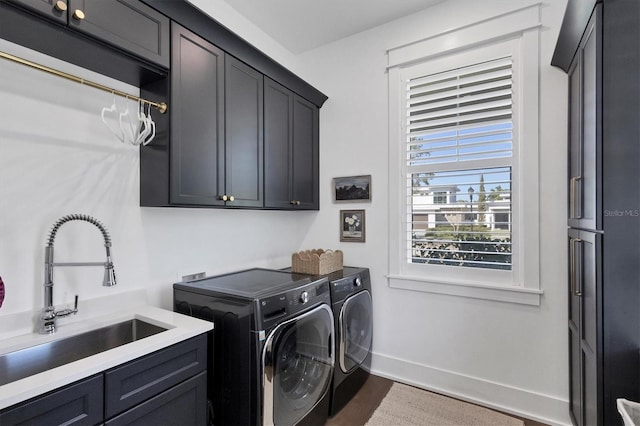 laundry area with cabinet space, baseboards, washer and clothes dryer, dark wood-type flooring, and a sink