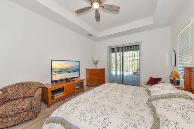 bedroom featuring a raised ceiling, ceiling fan, access to outside, and light hardwood / wood-style floors