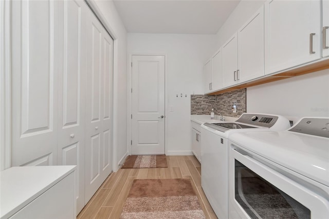 washroom with sink, washing machine and dryer, and cabinets