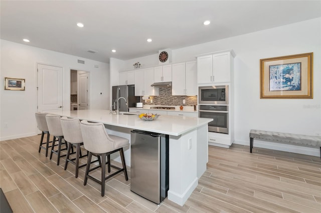 kitchen featuring white cabinetry, tasteful backsplash, stainless steel appliances, and a spacious island