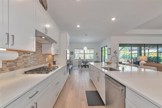 kitchen with sink, light hardwood / wood-style flooring, appliances with stainless steel finishes, white cabinetry, and tasteful backsplash