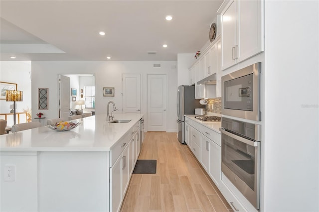 kitchen featuring white cabinets, sink, a large island with sink, and appliances with stainless steel finishes