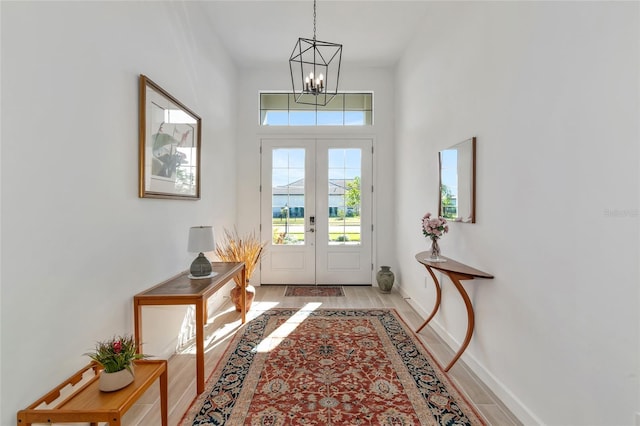 doorway to outside with an inviting chandelier, french doors, and light wood-type flooring