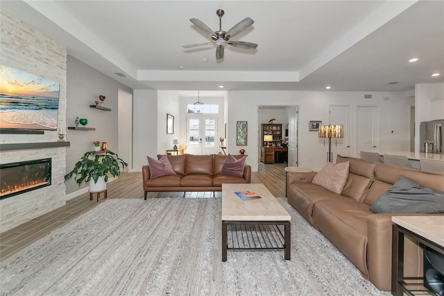 living room with french doors, a raised ceiling, and light hardwood / wood-style flooring