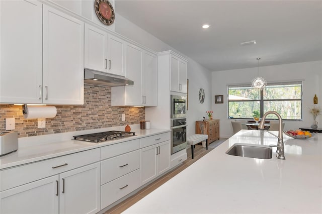 kitchen featuring pendant lighting, sink, appliances with stainless steel finishes, white cabinetry, and tasteful backsplash