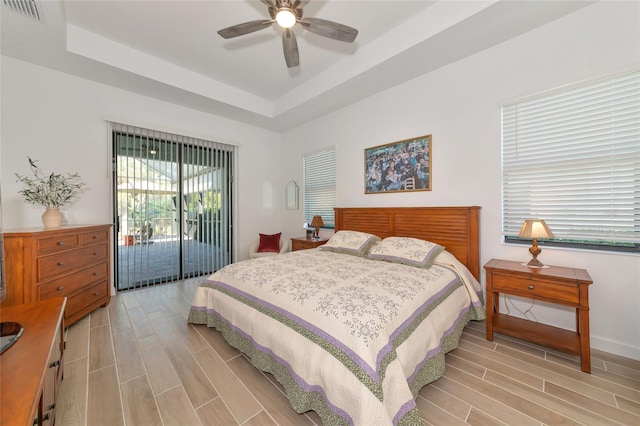 bedroom featuring ceiling fan, a raised ceiling, and access to outside