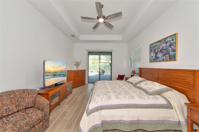 bedroom featuring ceiling fan, access to exterior, and a raised ceiling