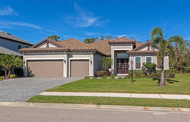 mediterranean / spanish home with french doors, a garage, and a front lawn