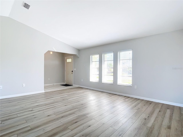 empty room featuring vaulted ceiling and light hardwood / wood-style flooring