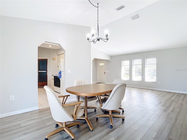 dining room featuring a notable chandelier, vaulted ceiling, and light wood-type flooring