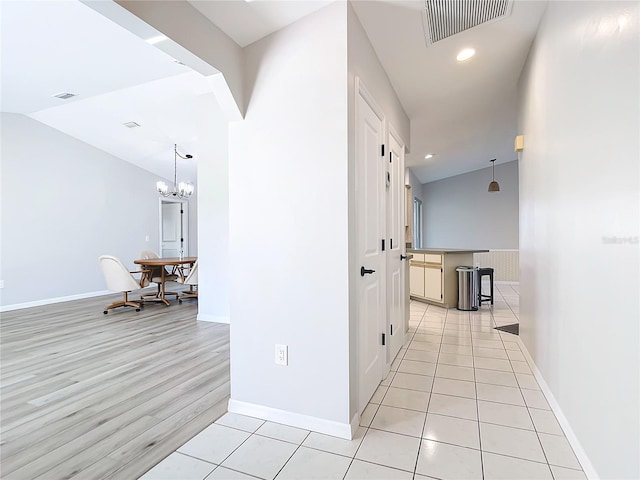 corridor featuring vaulted ceiling, light tile patterned floors, and a chandelier