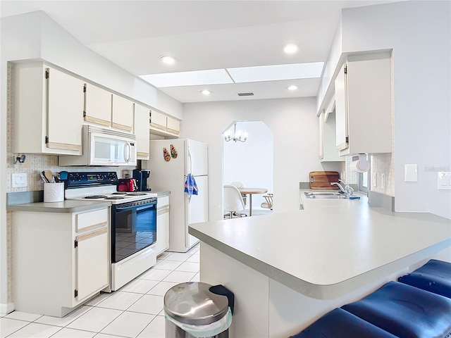 kitchen featuring light tile patterned flooring, white cabinetry, tasteful backsplash, kitchen peninsula, and white appliances