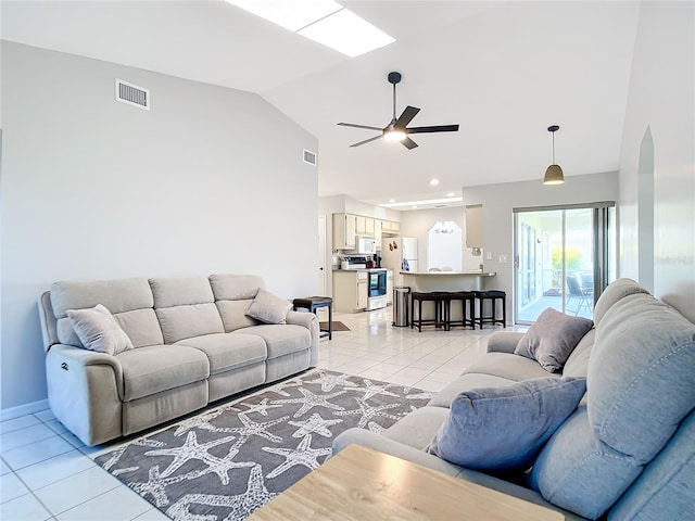 tiled living room with high vaulted ceiling, ceiling fan, and a skylight