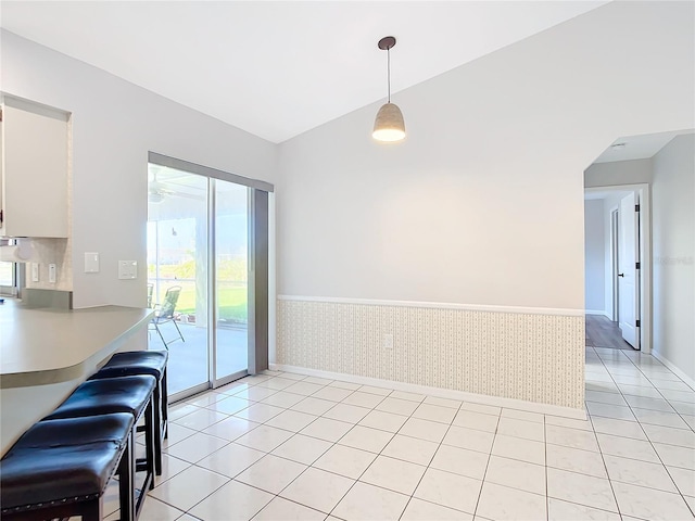 tiled dining area featuring vaulted ceiling