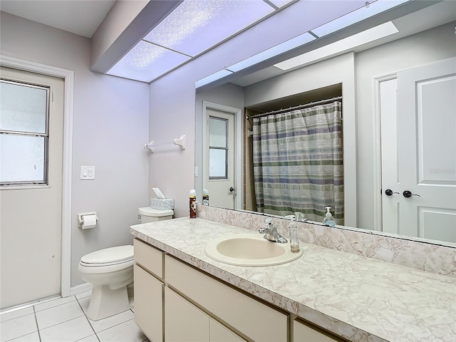 bathroom featuring tile patterned flooring, vanity, a skylight, and toilet