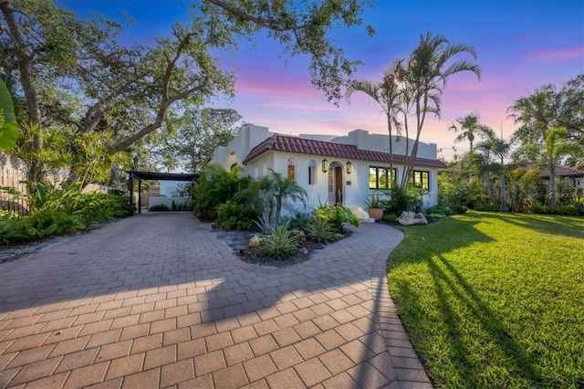 mediterranean / spanish-style house with a carport and a yard