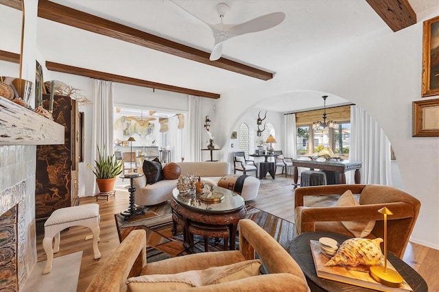 living room with a premium fireplace, a chandelier, beam ceiling, and light wood-type flooring