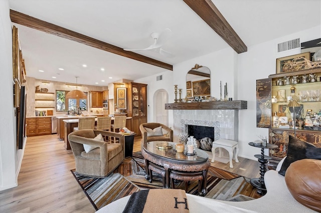 living room with beam ceiling, light hardwood / wood-style floors, and a tile fireplace