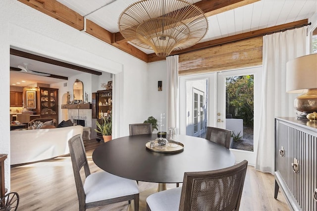 dining area with french doors, beam ceiling, and light wood-type flooring