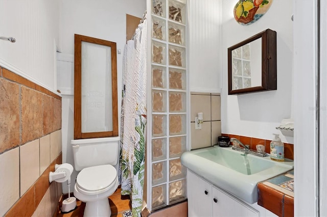 bathroom featuring vanity, tile walls, toilet, and walk in shower