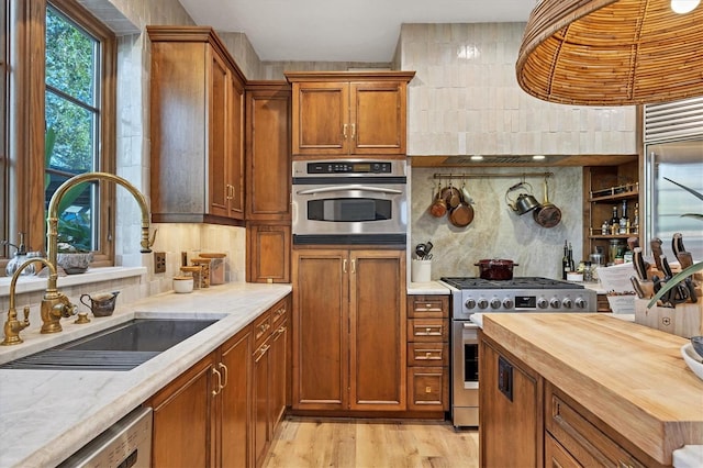 kitchen featuring sink, appliances with stainless steel finishes, butcher block counters, light hardwood / wood-style floors, and decorative backsplash