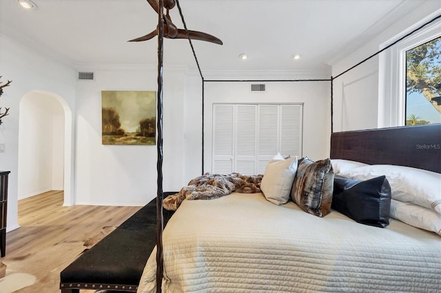 bedroom featuring crown molding, light hardwood / wood-style floors, a closet, and ceiling fan